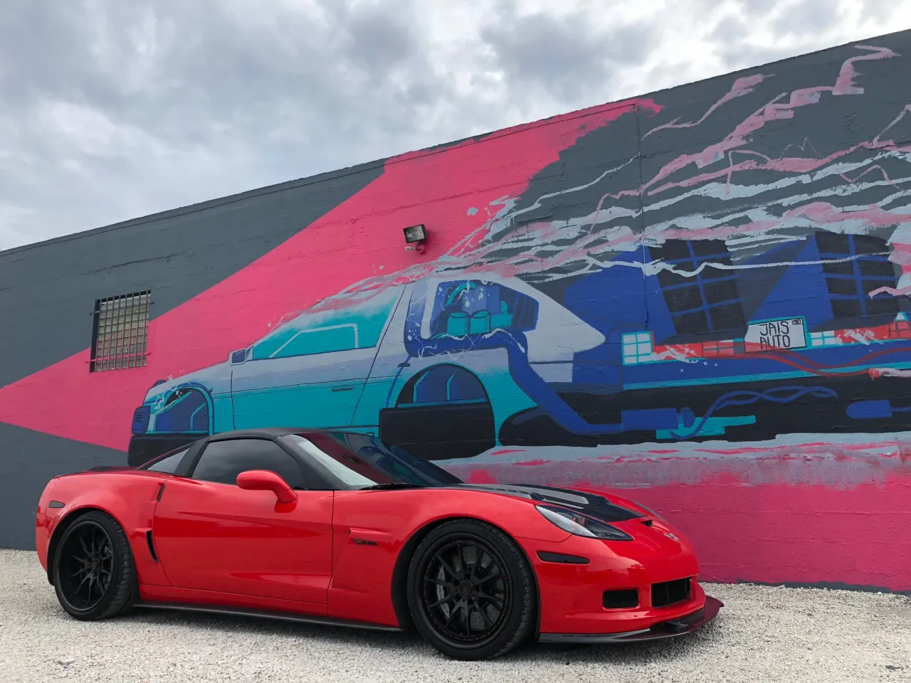 Red C6 Z06 in front of mural